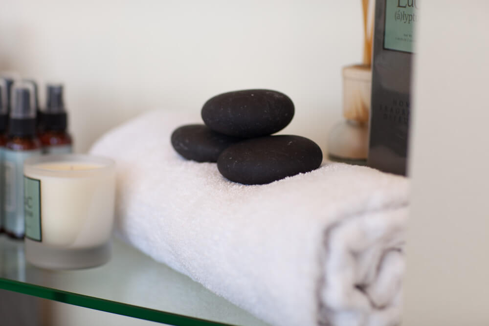Towel, hot stones and candle on shelf